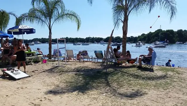 group gathering on beach with cornhole game