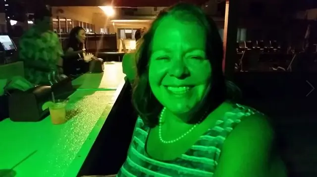 woman smiling under green lighting at bar