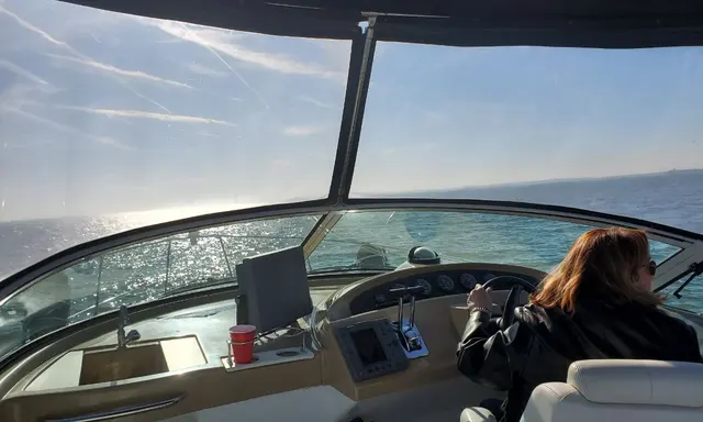 Woman (Lori) from behind driving boat with sunlit water; fully clothed