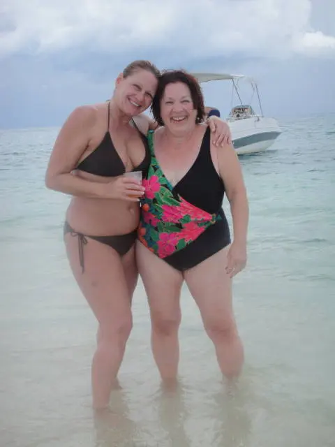 two women in swimsuits in water with boat