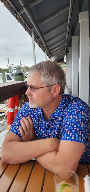 John enjoying a cocktail at a waterfront restaurant along the marina
