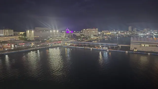 San Juan's skyline lit up in purple as the ship departs.