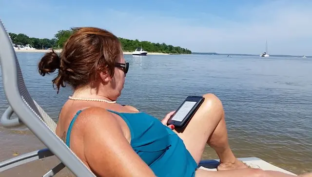 woman relaxing on beach chair reading tablet