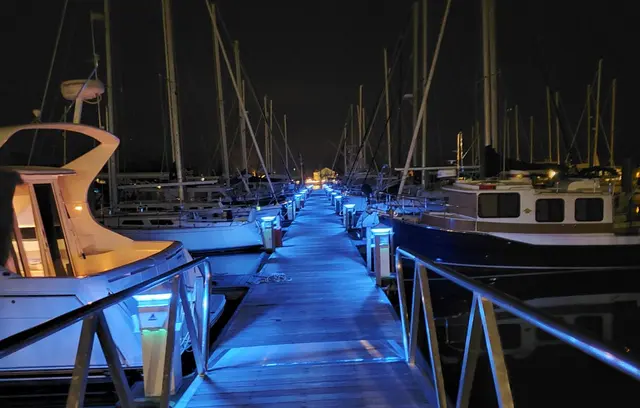 Marina docks at night with blue lighting and boats; scenery