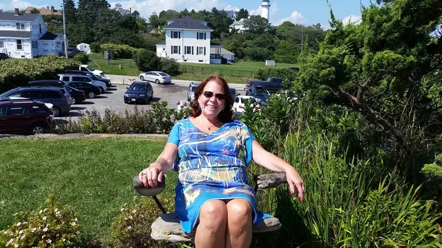 Lori relaxing on a stone bench with the lighthouse in view
