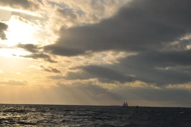 scenic sunset over ocean with sailboat