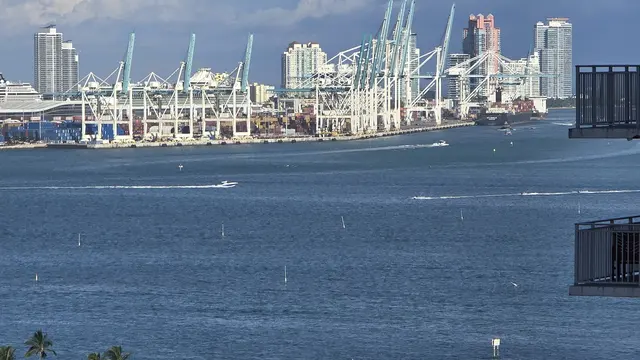 The Port of Miami with cranes, cargo ships, and speedboats crossing the bay.
