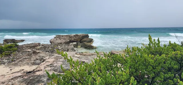 Dramatic waves crash against the rocky shoreline as a storm rolls in.