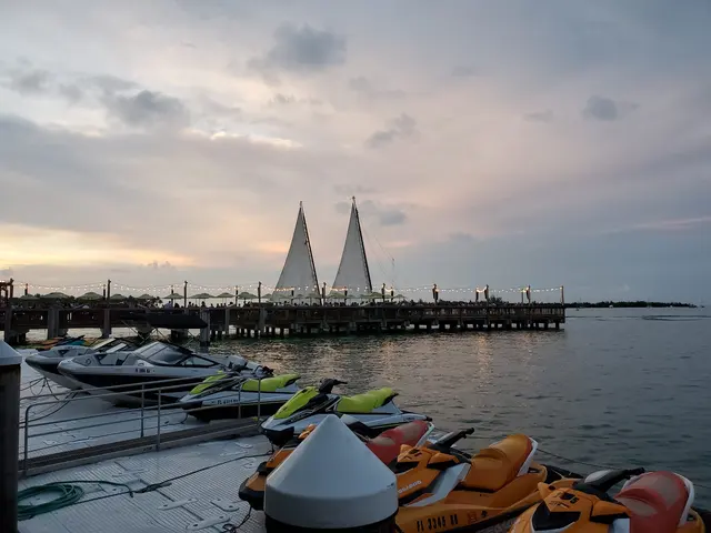 Jet skis and boats lined up at the marina as the sun sets.