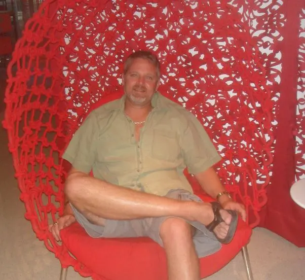 man sitting in red woven chair