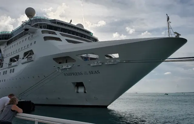 Cruise ship Empress of the Seas docked; scenery with two people at railing clothed