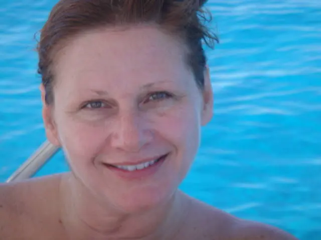 close crop of woman's face and bare shoulders in pool water; swimwear not visible in frame