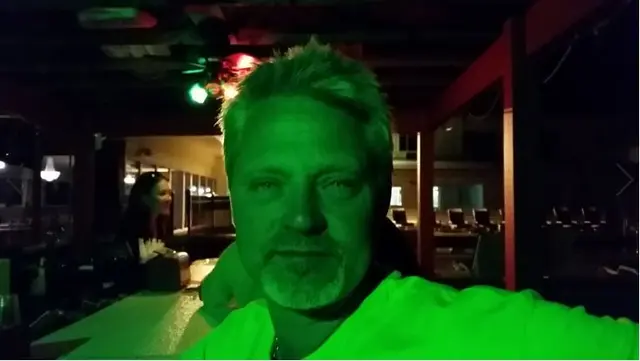 man selfie under green lighting at bar