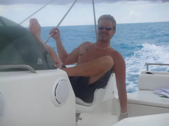 shirtless man sitting on boat at sea