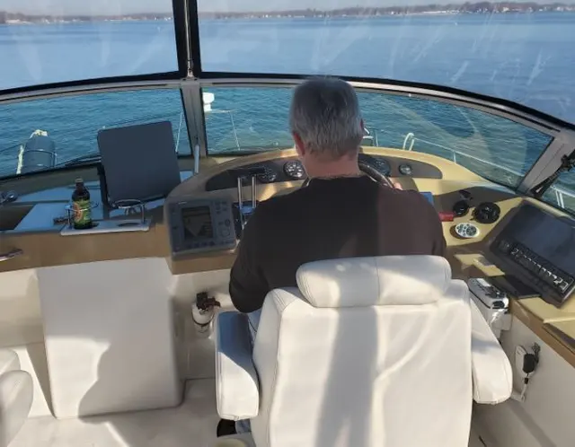 Man (John) from behind driving boat on open water; fully clothed