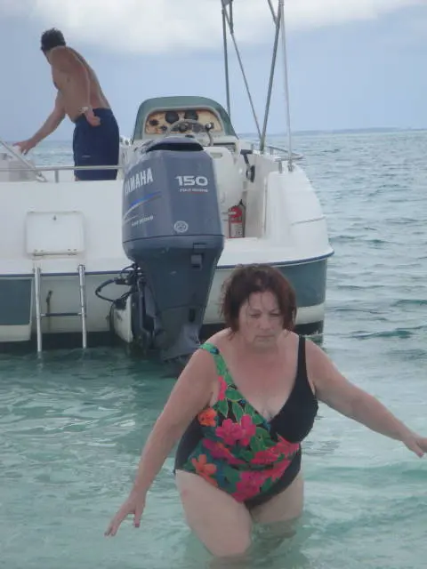 woman in swimsuit wading near boat