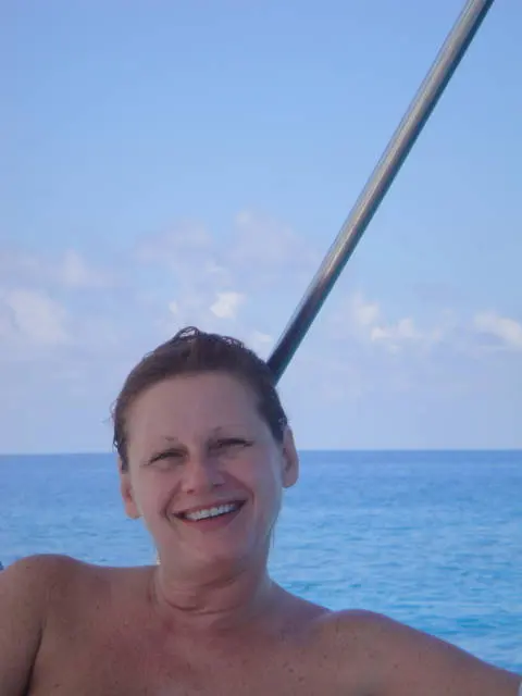 close crop of woman's face and bare shoulders on boat; swimwear not visible in frame