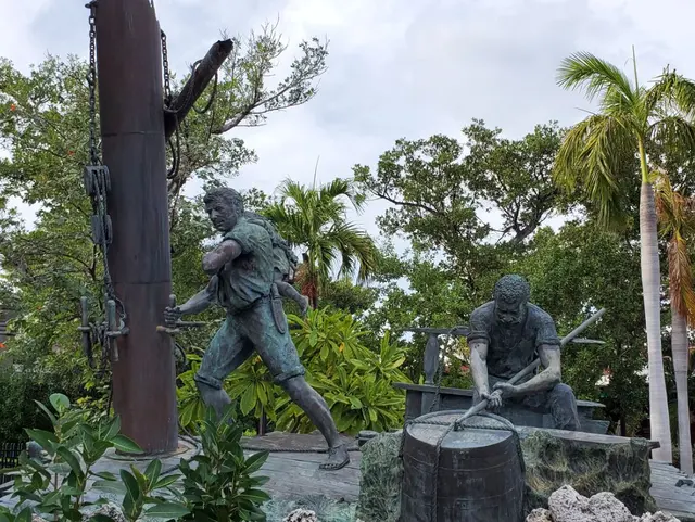Bronze wrecker/sailor statues in park with palm trees; scenery