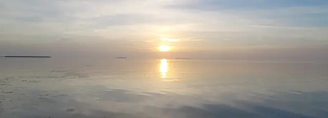 The sun dipping below the horizon, reflections on the water