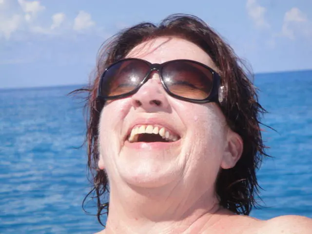 close crop of woman's face and bare shoulders looking up at sky; swimwear not visible in frame