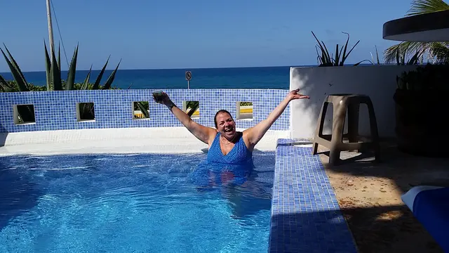 woman in swimsuit celebrating in rooftop pool