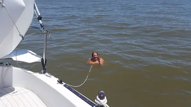 woman swimming in water behind boat