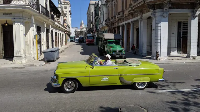 A lime green classic convertible turning onto Paseo de Marti