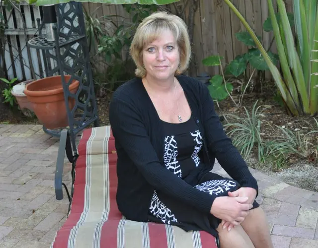 woman sitting on patio lounge chair in backyard