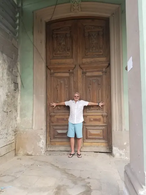 John striking a pose at a grand carved wooden doorway
