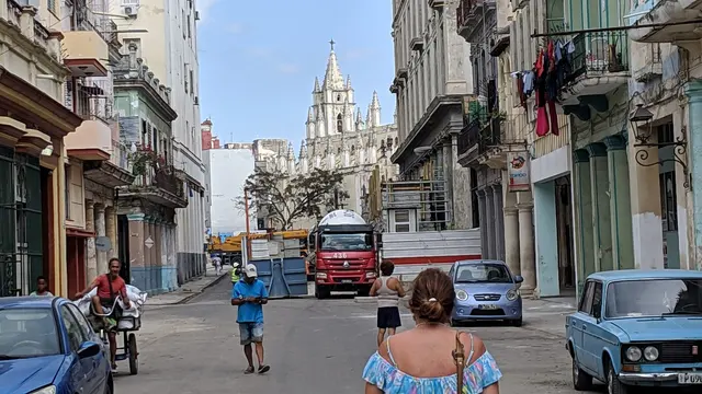 Lori walking a lively Havana street lined with classic cars