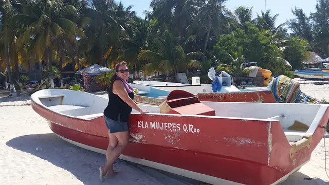 woman posing with fishing boat on beach