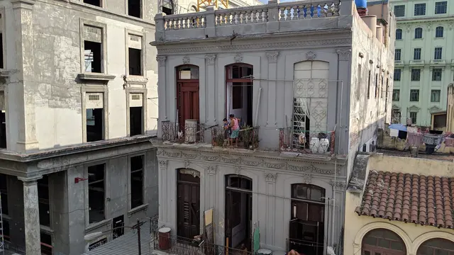 A family looks out from their balcony over the rooftops of Havana