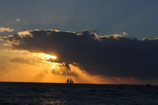 scenic sunset over ocean with sailboat silhouette