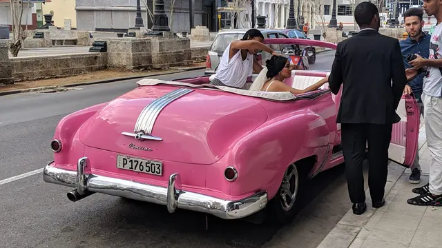A classic red convertible parked along the Havana waterfront
