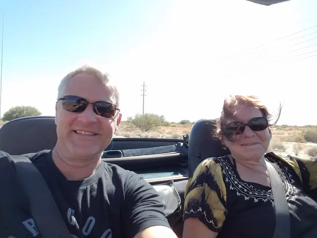 John and Lori all smiles in the convertible, desert scenery rolling by