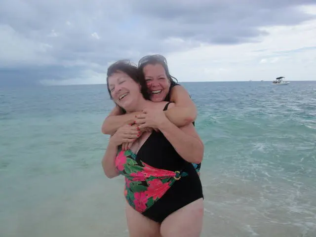 two women in swimsuits hugging in water