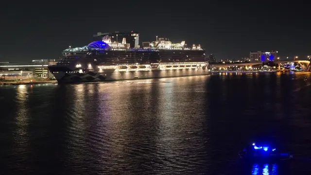 Returning to port at night, city lights sparkling on the water.