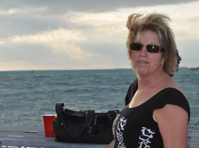 woman on pier by ocean with handbag