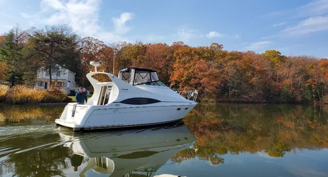 Man (John) docking white cabin cruiser boat by autumn shoreline; fully clothed