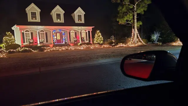 A neighborhood house lit up with holiday lights after dark.