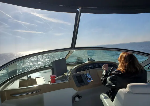 Woman (Lori) from behind at boat helm with red cup nearby; fully clothed