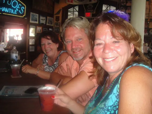 three people smiling at bar with drinks