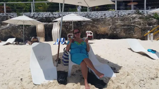 woman in blue dress sitting on beach lounge chair